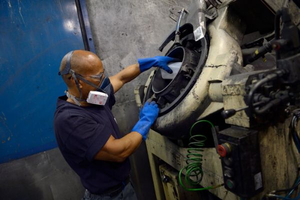 opérateur remplissant un broyeur pour le mélange de matières premières pour fabriquer des pièces métalliques