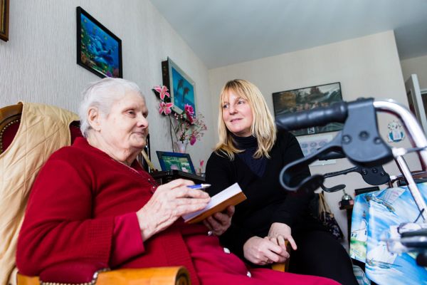 Auxiliaire de vie sociale aidant une usagère à la rédaction d’un liste de course