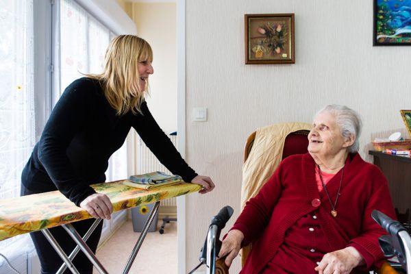 Auxiliaire de vie sociale faisant le repassage pour un usager à son domicile