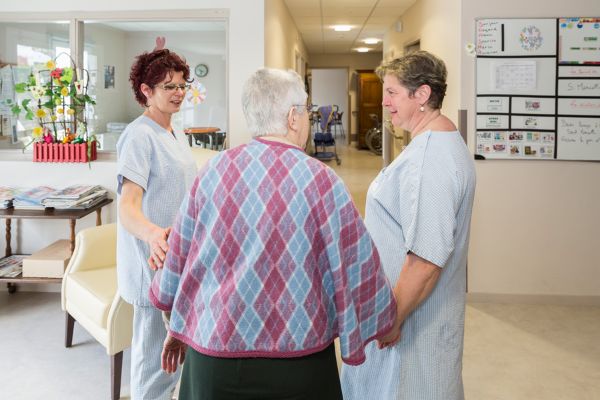 Une aide-soignante et un agent hôtelier en train d’échanger avec une résidente d’un EHPAD