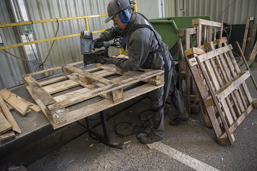 Travailleur réparant manuellement des palettes
