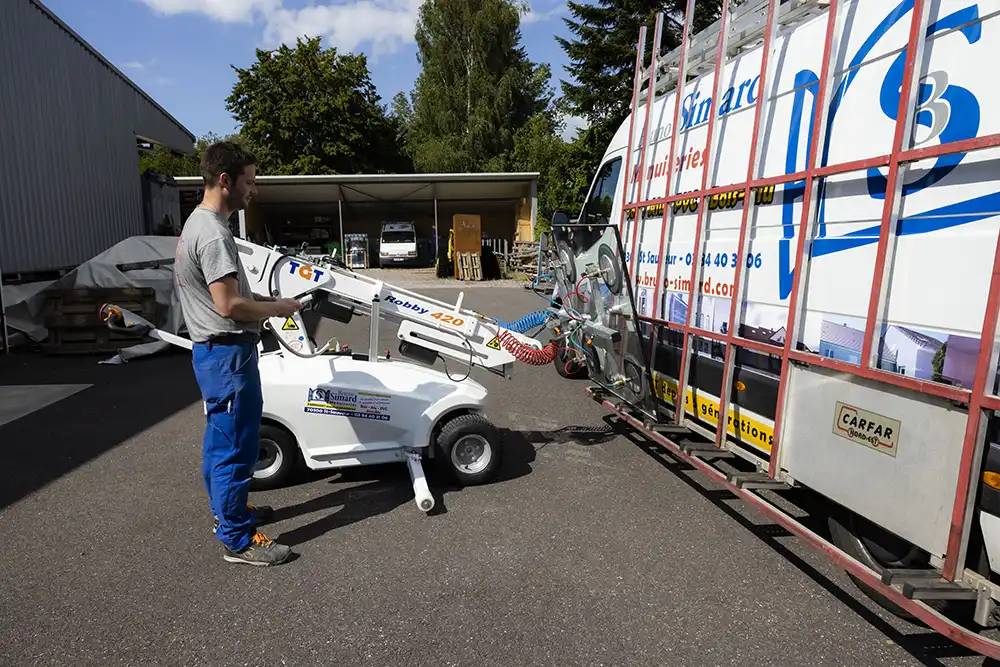 Un opérateur utilise un robot collaboratif pour déplacer une plaque en verre